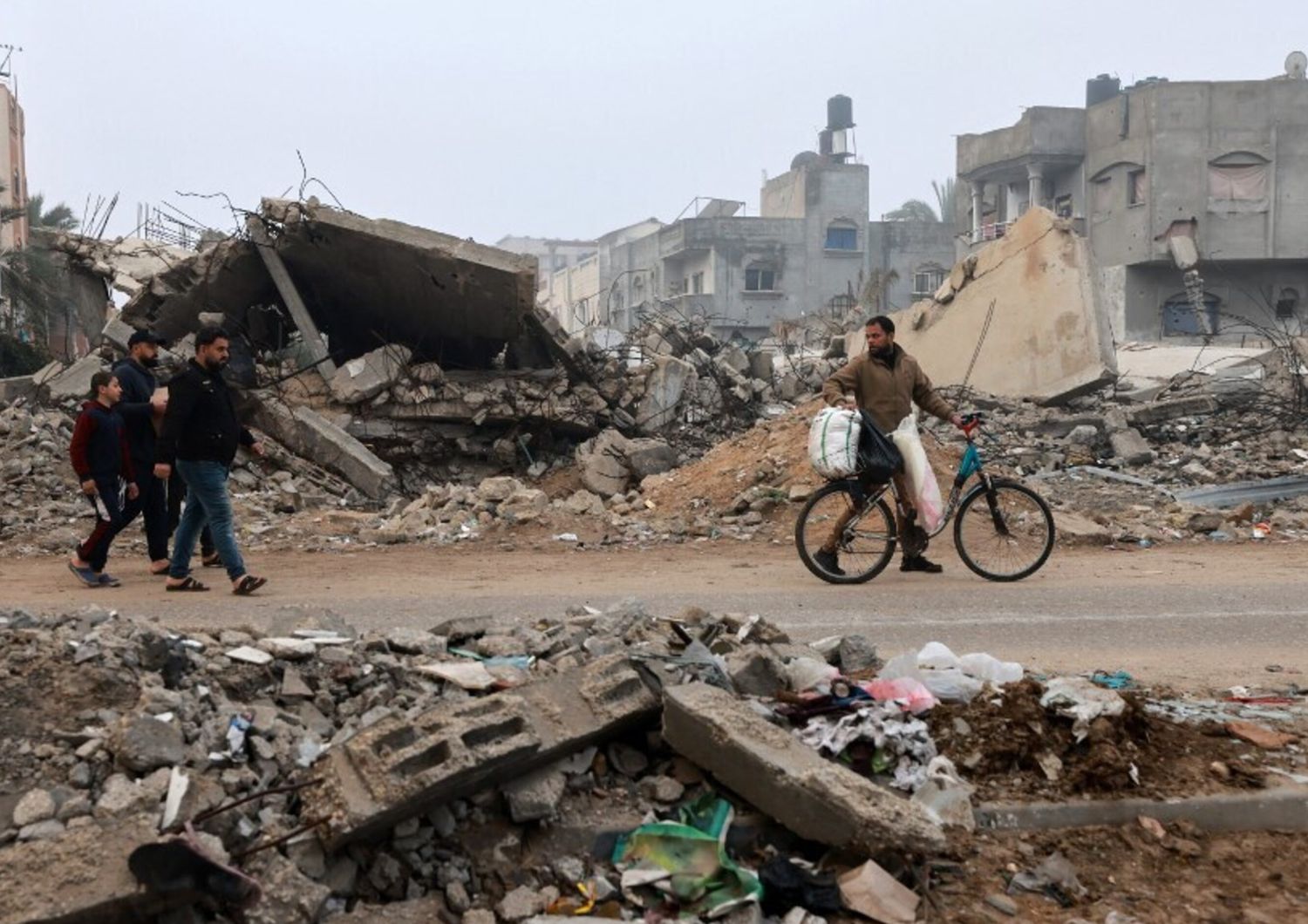 Uomini camminano lungo una strada devastata dai bombardamenti israeliani a Rafah, nel sud della Striscia di Gaza, il 9 febbraio 2024,