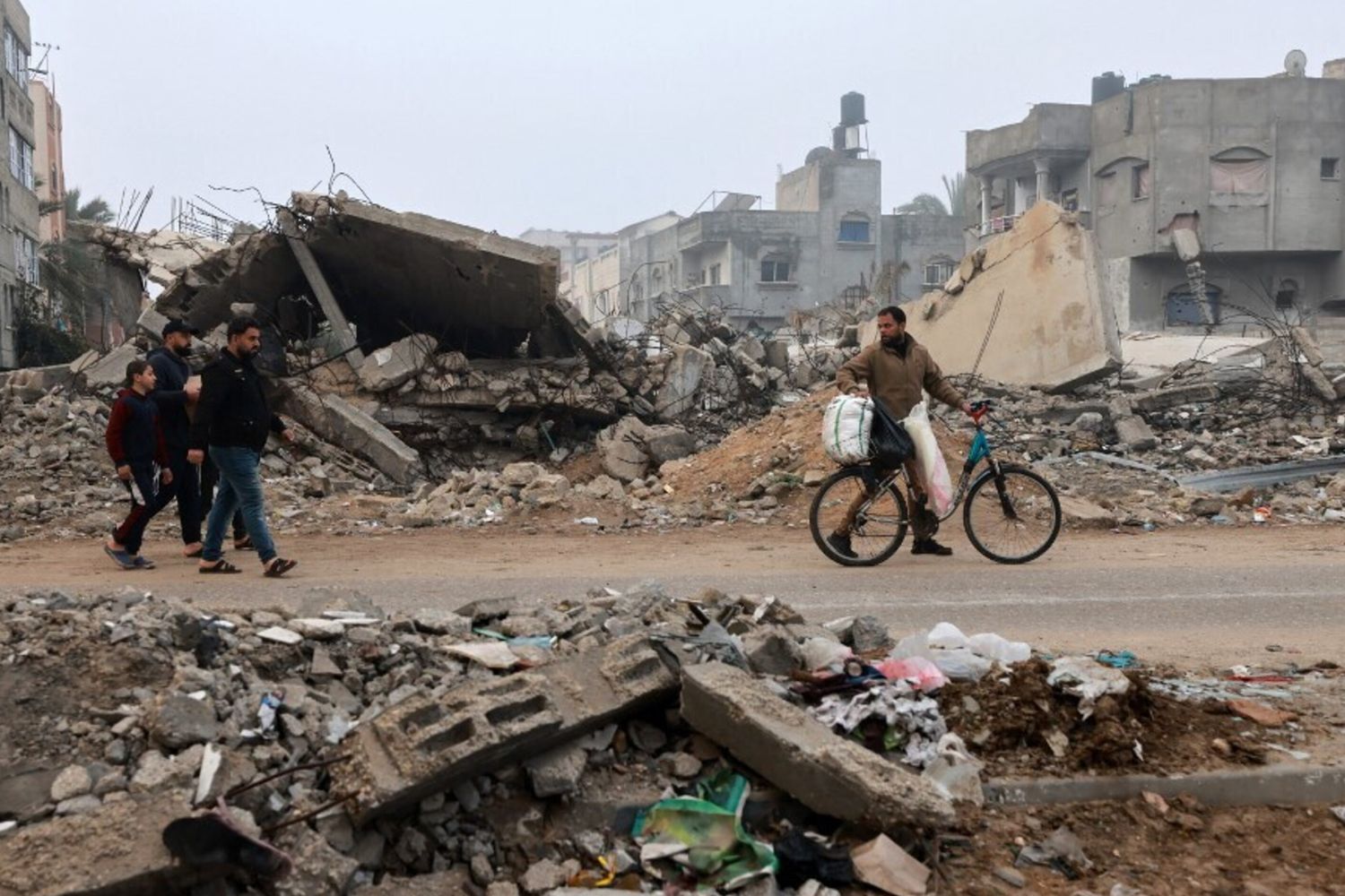 Uomini camminano lungo una strada devastata dai bombardamenti israeliani a Rafah, nel sud della Striscia di Gaza, il 9 febbraio 2024,