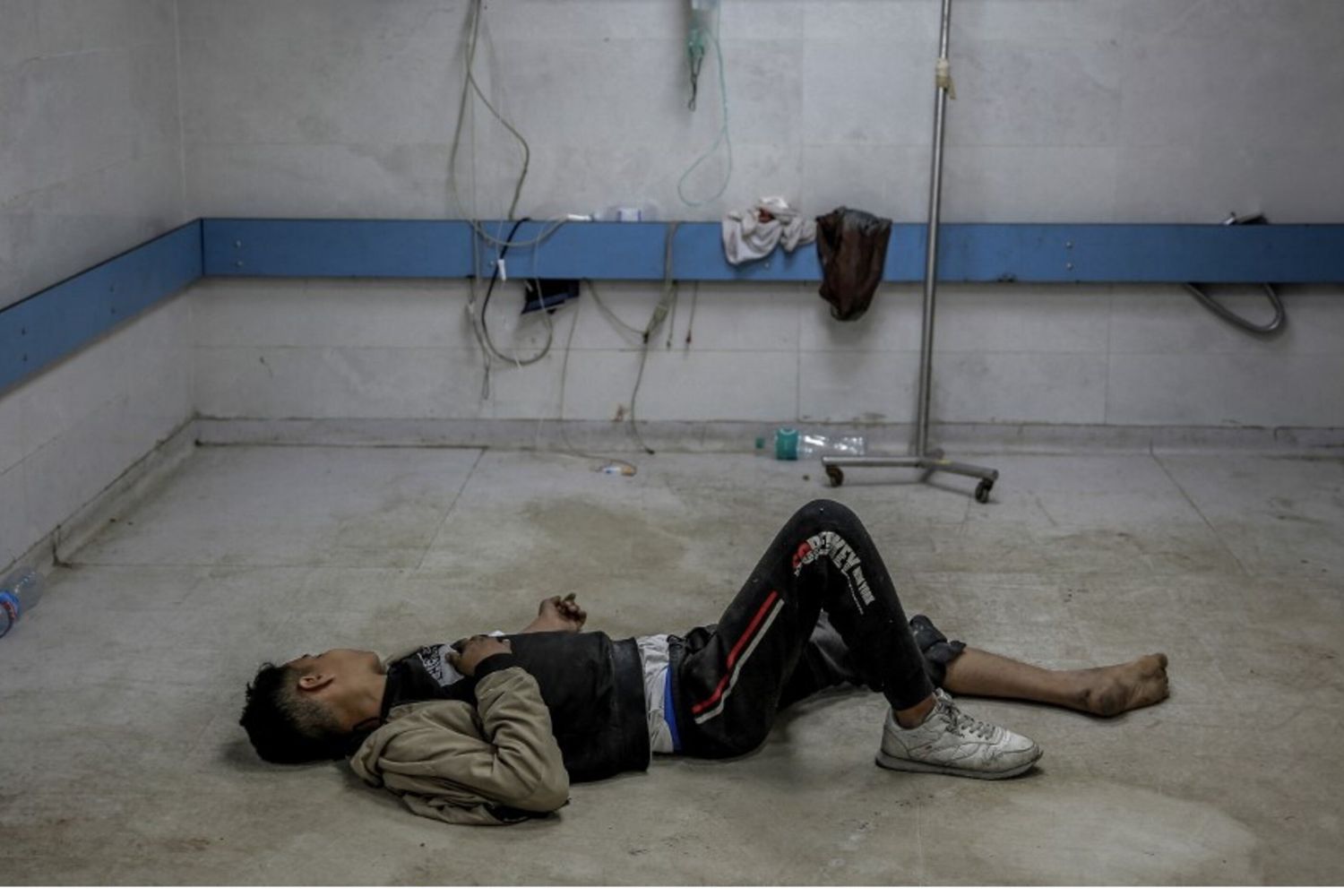 Un giovane palestinese ferito da un bombardamento israeliano giace a terra in attesa di cure mediche all'ospedale Al-Shifa di Gaza City