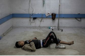 Un giovane palestinese ferito da un bombardamento israeliano giace a terra in attesa di cure mediche all'ospedale Al-Shifa di Gaza City