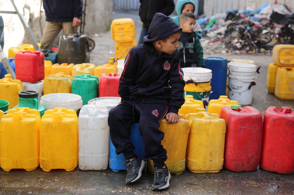 Bambini palestinesi raccolgono acqua nel quartiere di Zaytoun, a Gaza City, durante le battaglie in corso tra Israele e Hamas