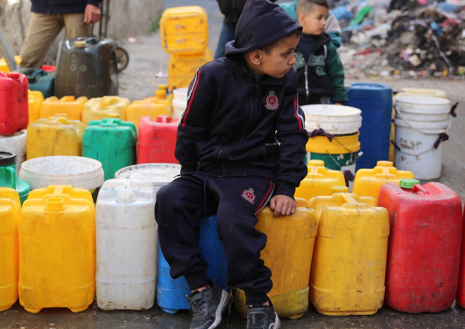 Bambini palestinesi raccolgono acqua nel quartiere di Zaytoun, a Gaza City, durante le battaglie in corso tra Israele e Hamas