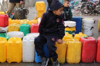 Bambini palestinesi raccolgono acqua nel quartiere di Zaytoun, a Gaza City, durante le battaglie in corso tra Israele e Hamas