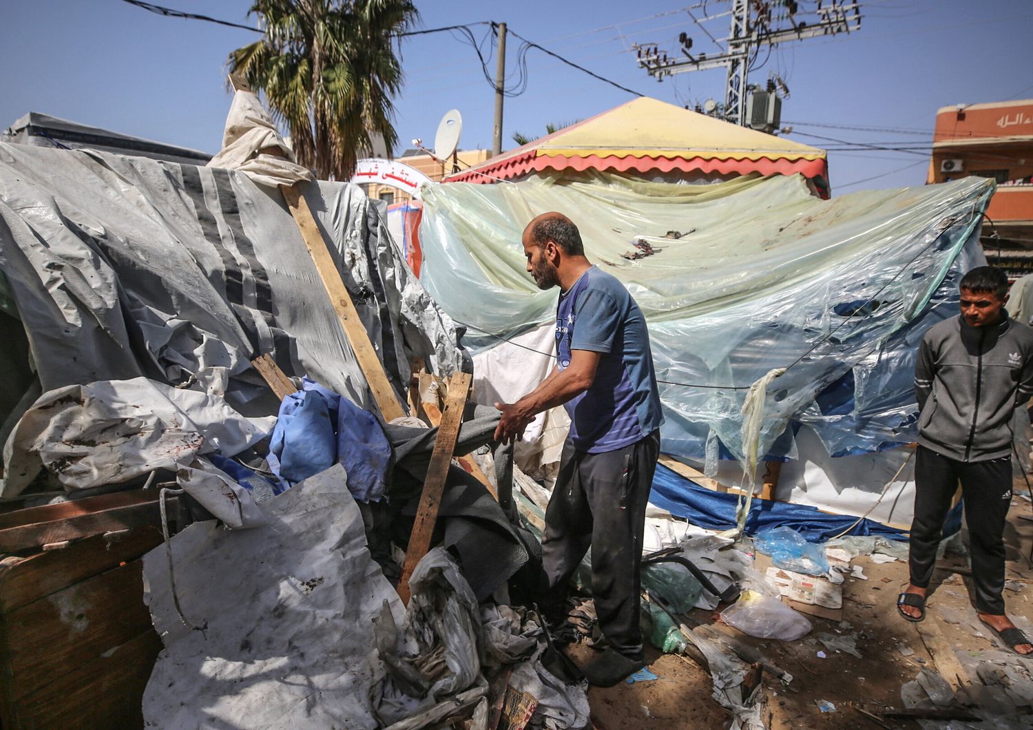 Alcuni palestinesi controllano i danni in un campo improvvisato per sfollati di fronte all'ospedale dei Martiri di Al-Aqsa a Deir al-Balah, nella Striscia di Gaza centrale, dopo che è stato colpito da un bombardamento israeliano il 31 marzo 2024