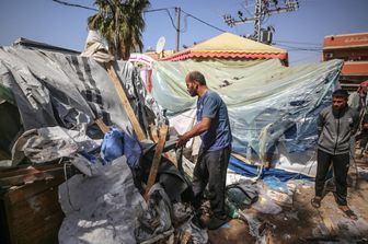 Alcuni palestinesi controllano i danni in un campo improvvisato per sfollati di fronte all'ospedale dei Martiri di Al-Aqsa a Deir al-Balah, nella Striscia di Gaza centrale, dopo che è stato colpito da un bombardamento israeliano il 31 marzo 2024