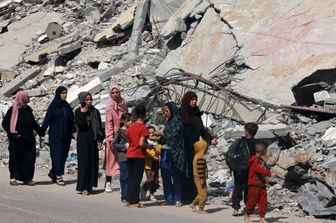 Donne e bambini palestinesi camminano vicino a un edificio distrutto da un bombardamento israeliano a Rafah, nel sud della Striscia di Gaza, il 31 marzo 2024