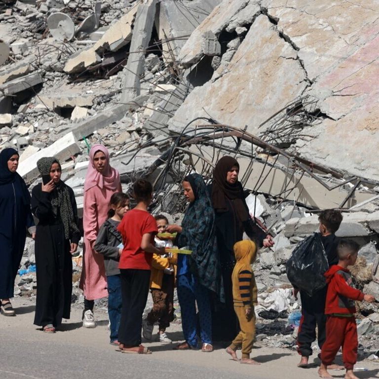 Donne e bambini palestinesi camminano vicino a un edificio distrutto da un bombardamento israeliano a Rafah, nel sud della Striscia di Gaza, il 31 marzo 2024