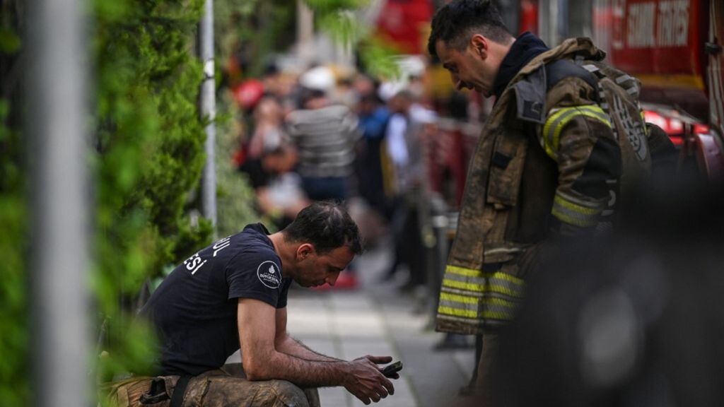 I vigili del fuoco in pausa durante l'intervento sul luogo di un incendio in un edificio residenziale a Istanbul