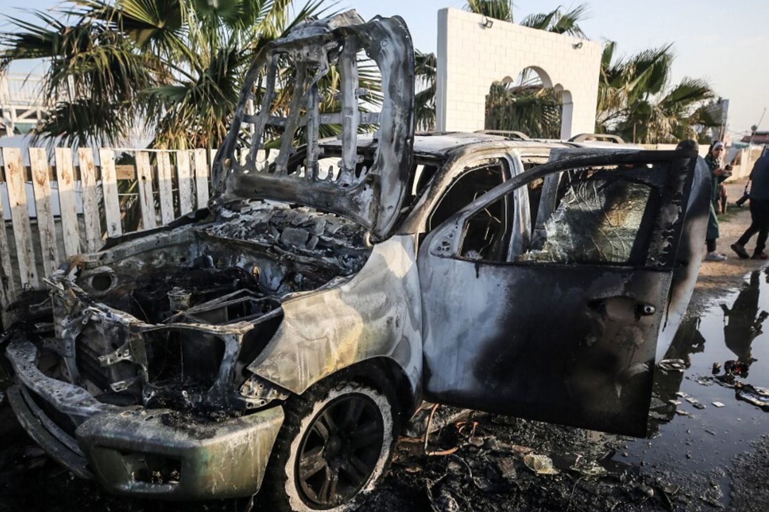 Palestinesi accanto a un veicolo a Deir Al-Balah, dove i dipendenti della World Central Kitchen (WCK) sono stati uccisi in un attacco aereo israeliano