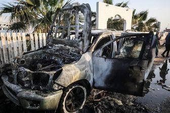 Palestinesi accanto a un veicolo a Deir Al-Balah, dove i dipendenti della World Central Kitchen (WCK) sono stati uccisi in un attacco aereo israeliano
