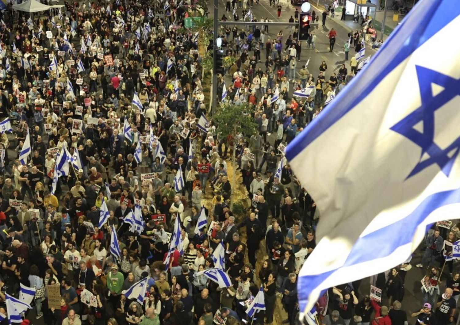 Parenti e sostenitori degli ostaggi israeliani detenuti a Gaza da parte dei militanti di Hamas tengono cartelli e sventolano bandiere israeliane durante una manifestazione davanti al Ministero della Difesa a Tel Aviv