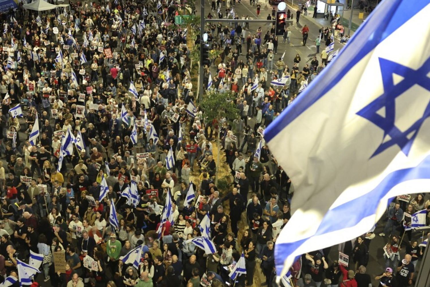 Parenti e sostenitori degli ostaggi israeliani detenuti a Gaza da parte dei militanti di Hamas tengono cartelli e sventolano bandiere israeliane durante una manifestazione davanti al Ministero della Difesa a Tel Aviv