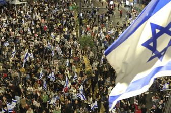 Parenti e sostenitori degli ostaggi israeliani detenuti a Gaza da parte dei militanti di Hamas tengono cartelli e sventolano bandiere israeliane durante una manifestazione davanti al Ministero della Difesa a Tel Aviv