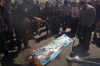Manifestanti iraniani bruciano una bandiera di Israele