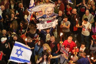Familiari degli ostaggi israeliani esibiscono cartelli, sventolano bandiere e tengono una caricatura del premier Netanyahu