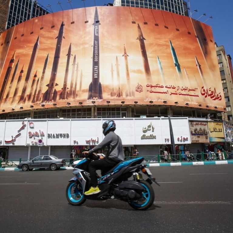 Un uomo passa in moto davanti a un cartellone pubblicitario che raffigura missili balistici iraniani in servizio a Teheran il 19 aprile 2024. I media statali iraniani hanno riferito di esplosioni nella provincia centrale di Isfahan