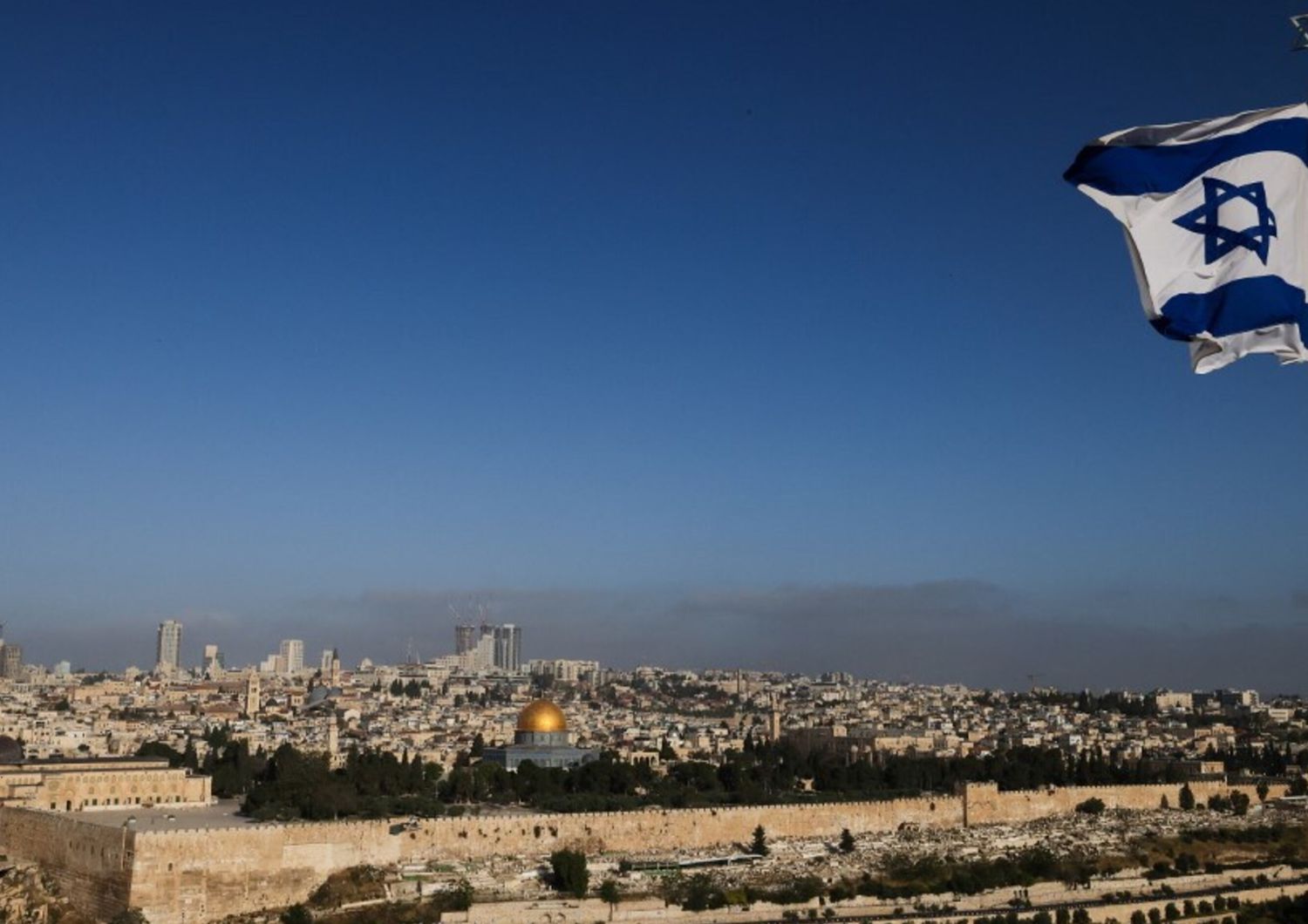 Una bandiera israeliana sventola sul Monte degli Ulivi che domina il complesso della moschea di Al Aqsa e lo skyline della città di Gerusalemme il 19 aprile 2024