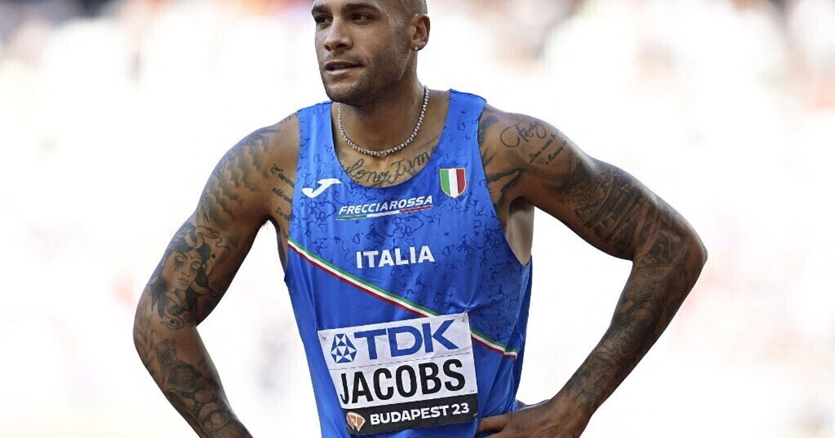 Un atleta italiano corre in pista, con bandiere a mezz'asta e un momento di silenzio per ricordare un campione