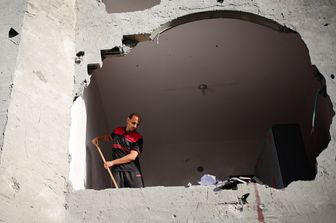 Macchie di sangue visibili sul muro mentre un uomo spazza le macerie di un edificio colpito dai bombardamenti israeliani a Rafah, nel sud della Striscia di Gaza, il 3 maggio 2024