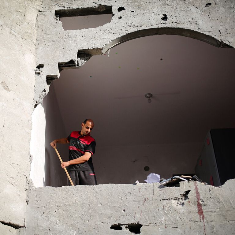 Macchie di sangue visibili sul muro mentre un uomo spazza le macerie di un edificio colpito dai bombardamenti israeliani a Rafah, nel sud della Striscia di Gaza, il 3 maggio 2024