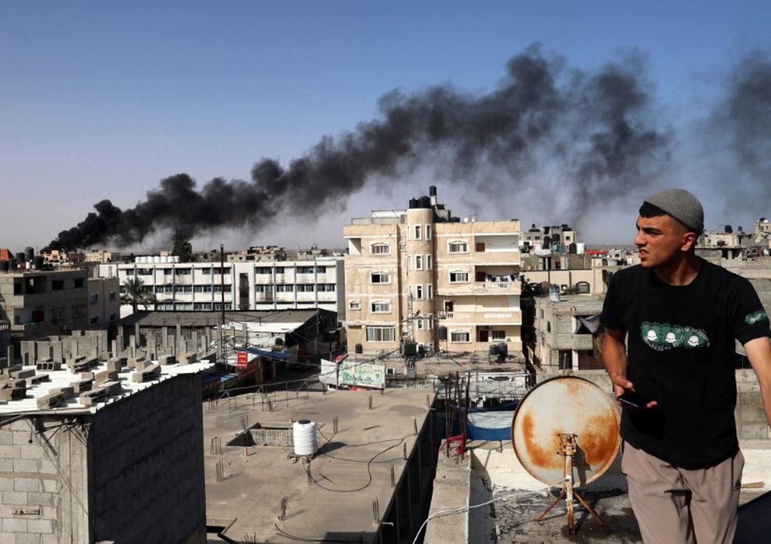 Un uomo osserva il fumo nero e denso che si leva dall'incendio di un edificio causato dai bombardamenti israeliani a Rafah, nel sud della Striscia di Gaza, il 10 maggio 2024