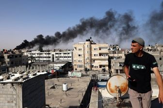 Un uomo osserva il fumo nero e denso che si leva dall'incendio di un edificio causato dai bombardamenti israeliani a Rafah, nel sud della Striscia di Gaza, il 10 maggio 2024