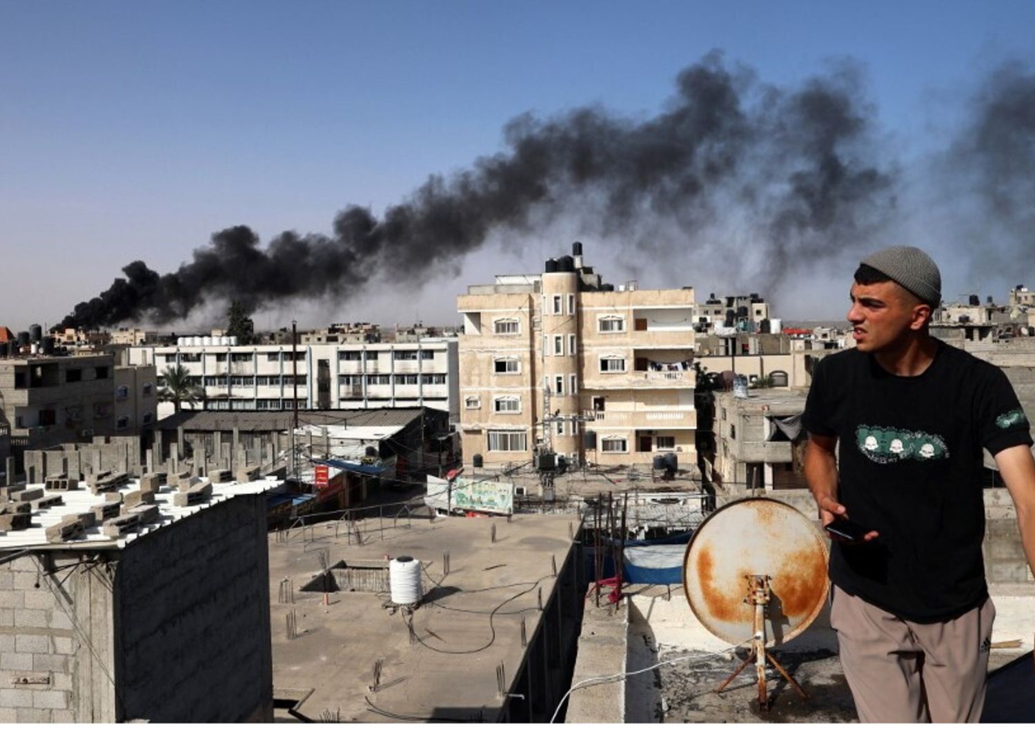 Un uomo osserva il fumo nero e denso che si leva dall'incendio di un edificio causato dai bombardamenti israeliani a Rafah, nel sud della Striscia di Gaza