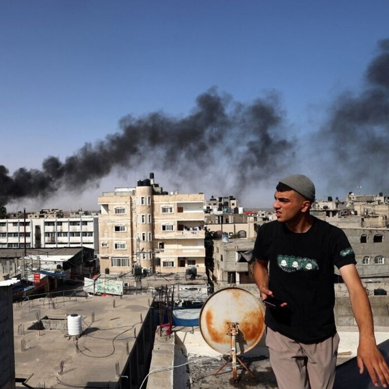 Un uomo osserva il fumo nero e denso che si leva dall'incendio di un edificio causato dai bombardamenti israeliani a Rafah, nel sud della Striscia di Gaza, il 10 maggio 2024