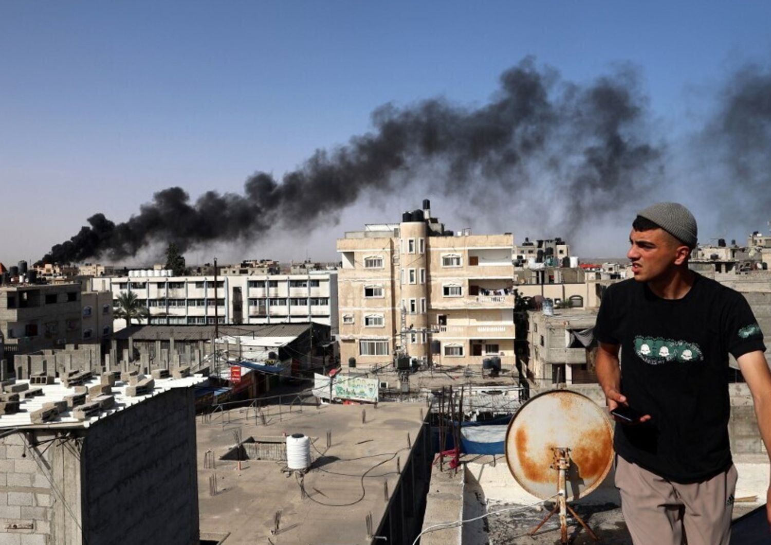 Un uomo osserva il fumo nero e denso che si leva dall'incendio di un edificio causato dai bombardamenti israeliani a Rafah, nel sud della Striscia di Gaza, il 10 maggio 2024