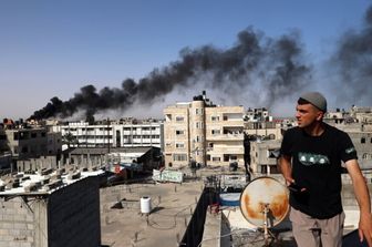 Un uomo osserva il fumo nero e denso che si leva dall'incendio di un edificio causato dai bombardamenti israeliani a Rafah, nel sud della Striscia di Gaza, il 10 maggio 2024