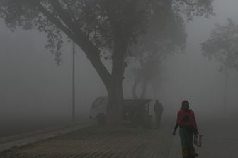 Una donna cammina a Nuova Delhi, in India, circondata dallo smog