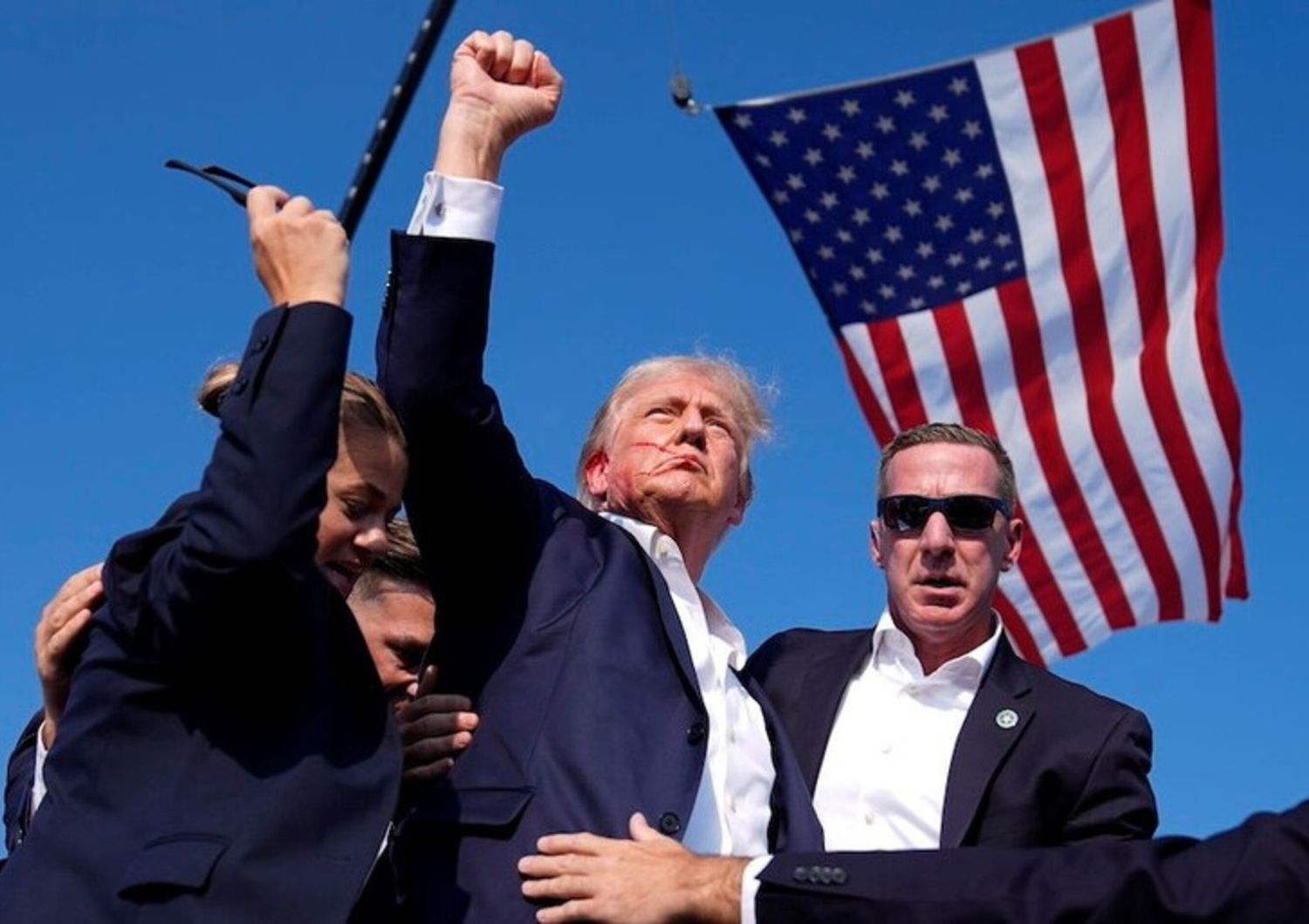 La foto iconica dell'AP dopo l'attentato di Trump insanguinato e con il pugno alzato con alle spalle la bandiera Usa