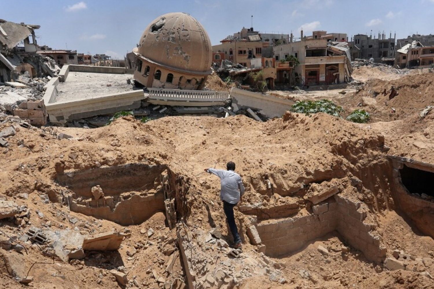 Un palestinese ispeziona un'area scavata dove l'esercito israeliano avrebbe condotto operazioni prima di ritirarsi nella città di Bani Suhayla, nel sud della Striscia di Gaza