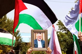 Persone reggono la bandiera palestinese e un ritratto del capo di Hamas Ismail Haniyeh, assassinato, durante una manifestazione all'Università di Teheran, nella capitale iraniana Teheran, il 31 luglio 2024, mentre l'Iran dichiara tre giorni di lutto