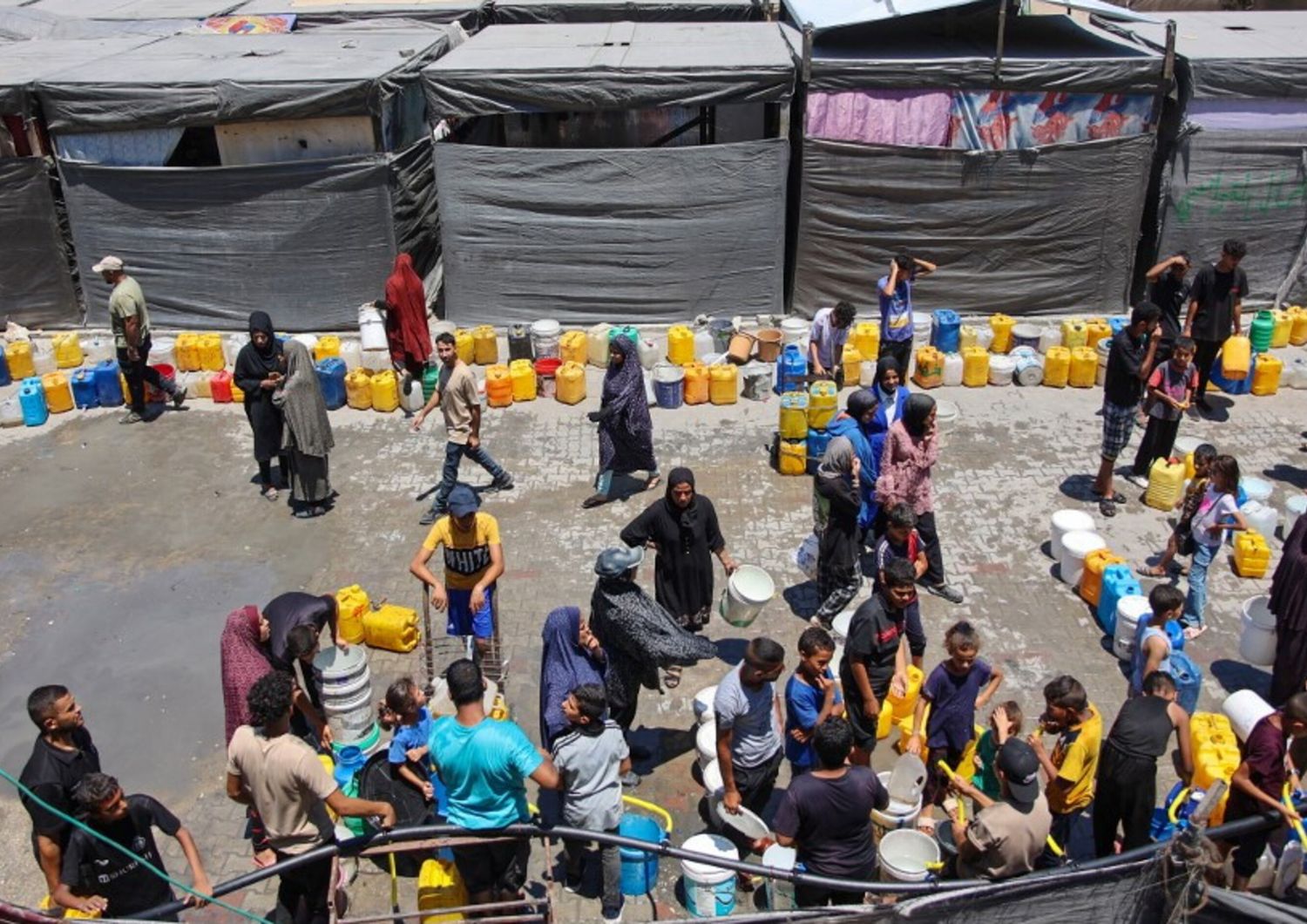 Réfugiés palestiniens font la queue pour remplir des bidons d'eau