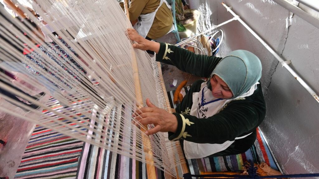 Une femme tunisienne tisse un tapis traditionnel dans un atelier , 2024