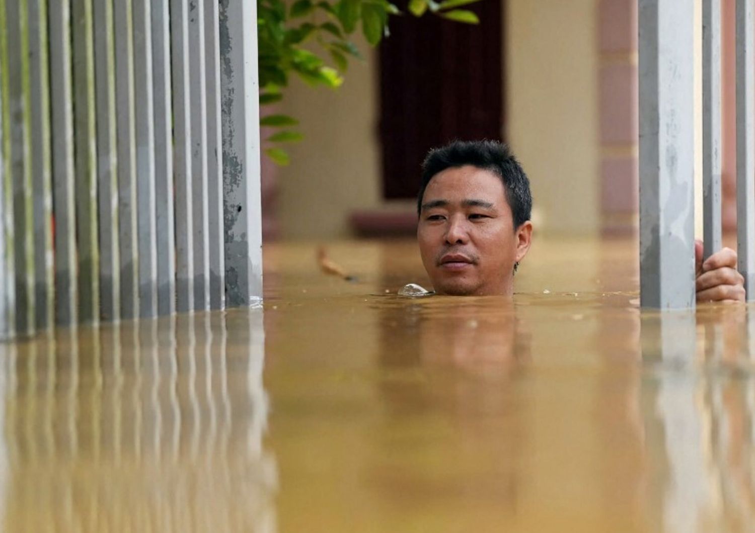 Un uomo attraversa le acque alluvionali fuori dalla sua casa nella provincia di Thai Nguyen