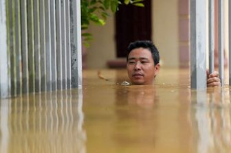 Un uomo attraversa le acque alluvionali fuori dalla sua casa nella provincia di Thai Nguyen