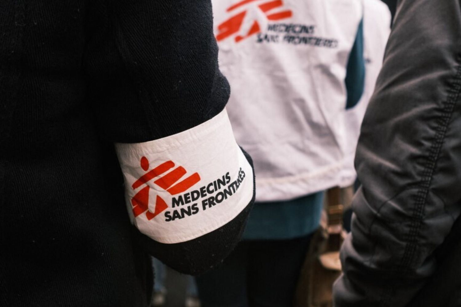 Un manifestante francese contro la legge sull'immigrazione davanti all'Assemblea Nazionale che indossa una fascia di Medici senza frontiere