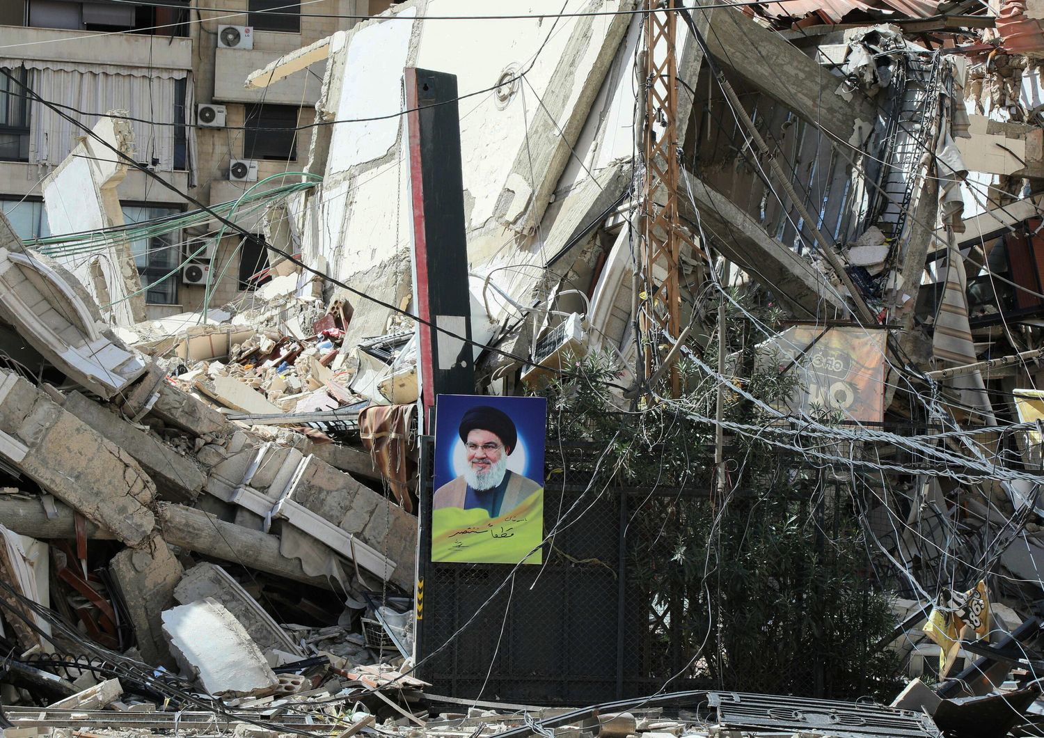 Un ritratto del leader ucciso del gruppo, Hassan Nasrallah, appeso alle macerie di un edificio distrutto da un attacco aereo israeliano su un quartiere della periferia meridionale di Beirut