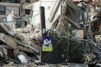 Un ritratto del leader ucciso del gruppo, Hassan Nasrallah, appeso alle macerie di un edificio distrutto da un attacco aereo israeliano su un quartiere della periferia meridionale di Beirut