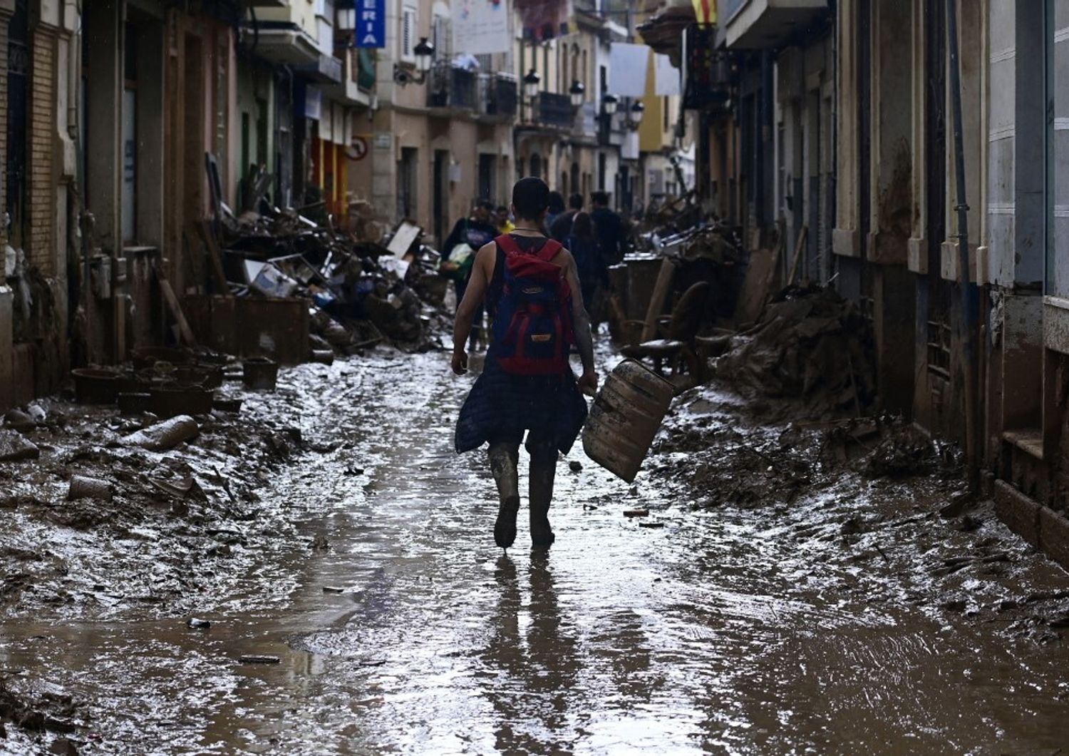 Un volontario cammina su una strada fangosa mentre lascia Paiporta, nella regione di Valencia, nella Spagna orientale