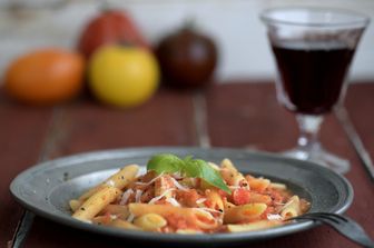 Un piatto di pasta accompagnato da un bicchiere di vino