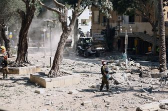 Un soccorritore israeliano si trova tra le macerie di un edificio colpito durante un attacco iraniano nella città portuale di Haifa