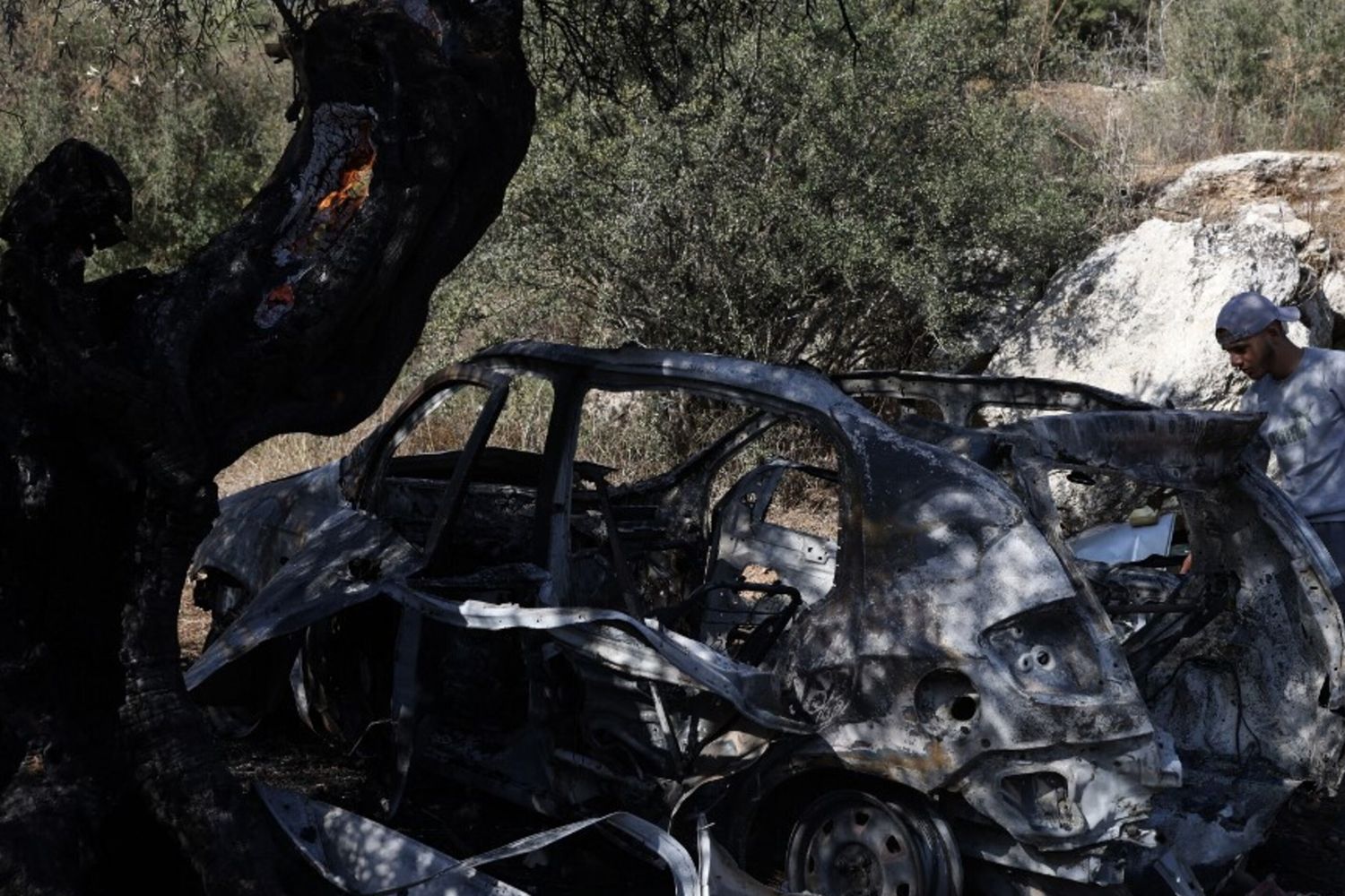 Un palestinese osserva i rottami di un veicolo nel luogo in cui tre palestinesi sono stati uccisi dalle forze israeliane durante un raid nel villaggio di Kafr