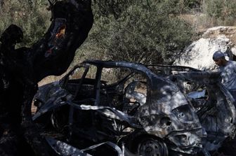 Un palestinese osserva i rottami di un veicolo nel luogo in cui tre palestinesi sono stati uccisi dalle forze israeliane durante un raid nel villaggio di Kafr