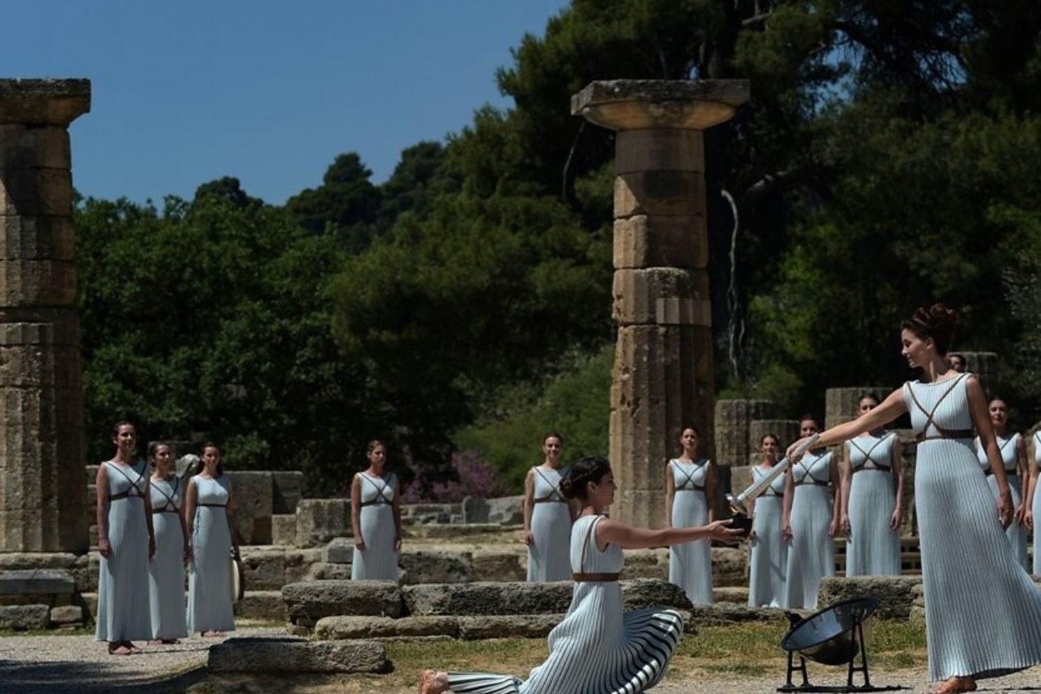&nbsp;Katerina Lexou porge la torcia accesa con la fiamma Olimpica &nbsp;ad un'altra attrice durante la cerimonia di accensione al Tempio di Hera&nbsp;(foto Afp)