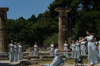 &nbsp;Katerina Lexou porge la torcia accesa con la fiamma Olimpica &nbsp;ad un'altra attrice durante la cerimonia di accensione al Tempio di Hera&nbsp;(foto Afp)
