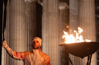 Il vogatore Stefanos Ntouskos tiene la Fiamma Olimpica davanti al Partenone di Atene