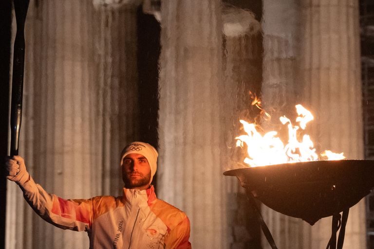 Il vogatore Stefanos Ntouskos tiene la Fiamma Olimpica davanti al Partenone di Atene